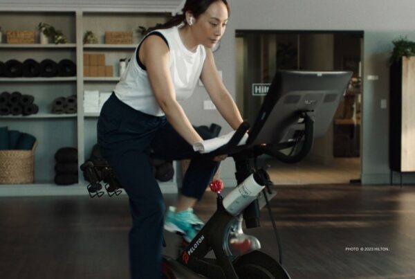 Peloton Bikes are being added to fitness centers in Hilton properties in Puerto Rico, Germany, the United Kingdom and participating hotels in Canada this year as the result of an expanded partnership between Peloton and Hilton. This image shows a woman riding a Peloton Bike in a Hilton property fitness center. Photo © 2023 Hilton.