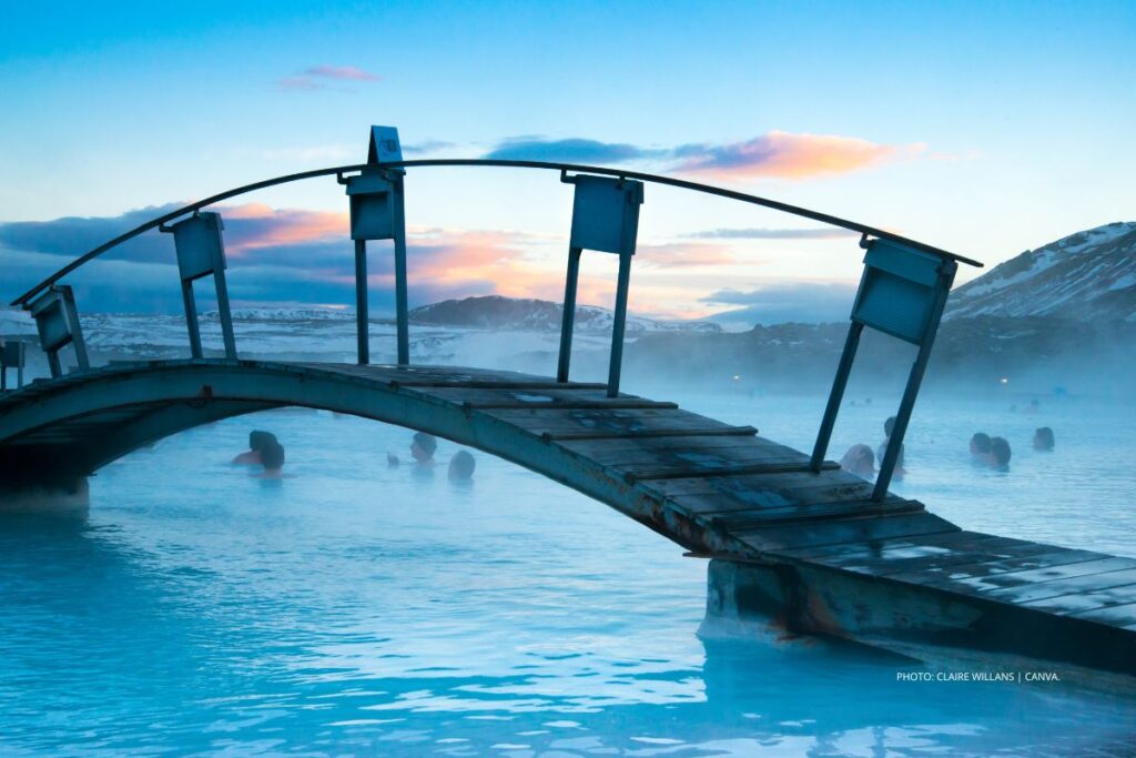 This is an image of a thermal pool, bridge and swimmers in Iceland's Blue Lagoon. Photo by Claire Willans | Canva.