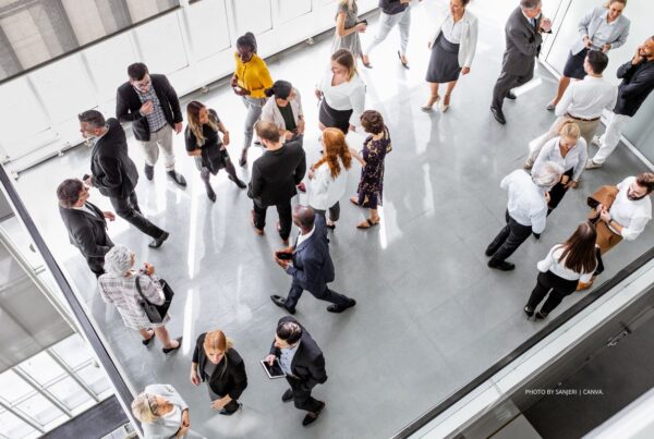 This is a stock photo by Sanjeri | Canva, showing business event attendees milling around an event space.