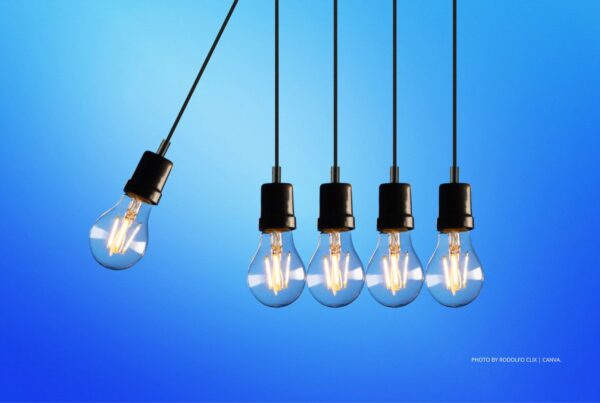 Positive change is the focus of a new team at IMEX Group. This image shows one lightbulb swinging towards four still lightbulbs on a blue background. Photo by Rodolfo Clix | Canva.