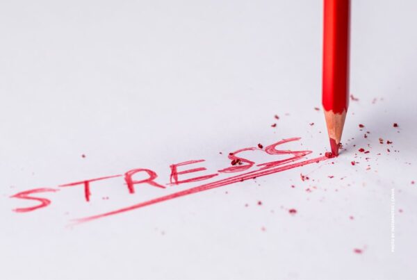 This is an image of a red pencil that has written and underlined the word Stress on a white background. Photo by Pedro Figueras | Canva.