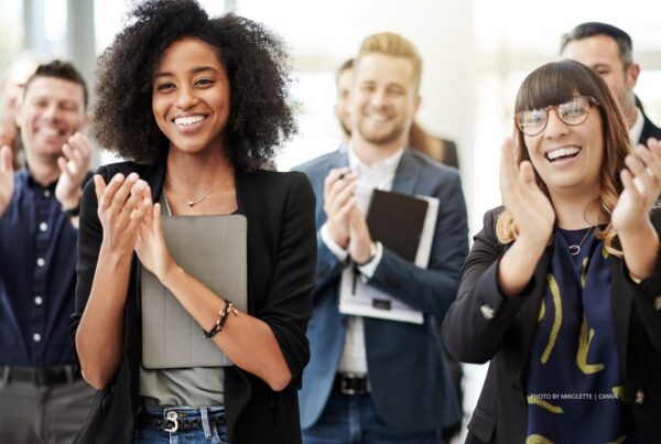 This is a stock image of a group of employees laughing and applauding someone/something. Photo by Mikolette | Canva.