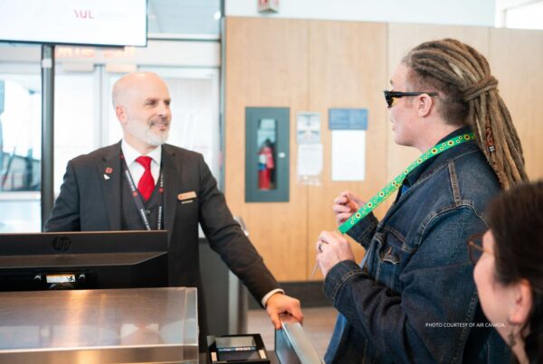 This image shows an Air Canada customer service representative (left) speaking to a person wearing a Hidden Disabilities Sunflower lanyard. Photo courtesy of Air Canada.