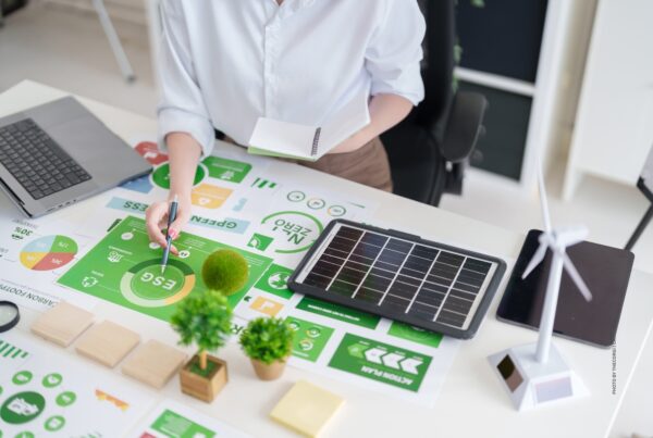This is a stock photo of a woman sitting at a desk sorting sustainability-related date. Photo by thecorgi | Canva.