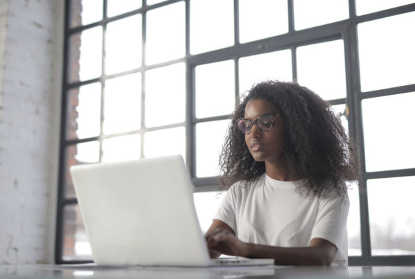 Image of woman in white t-shirt in front of white laptop. Used with article on Events Industry Council expanding testing options due to COVID-19. Photo by Andrea Piacquadio | Canva.