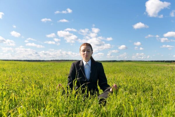 Wellness at MICE events is the topic of the newest study from the Incentive Research Foundation. Photo here shows a businesswoman meditating in a green field. Photo by 97 from Getty Images Signature | Canva.