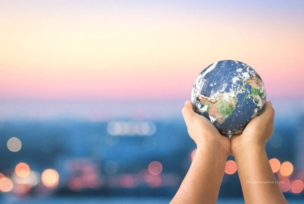 Enhanced Sustainable Event Standards have been launched by the Events Industry Council's Centre for Sustainability & Social Impact. The image here shows a woman holding a miniature globe in front of a blurred cityscape background. Photo by Boonyachoat | Canva.