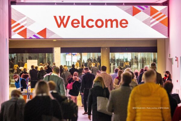 Visitor registration is open for IBTM World 2022. This image shows attendees walking through entrance marked "Welcoome" at IBTM World 2021, Fira Barcelona. Photo is courtesy of IBTM World.