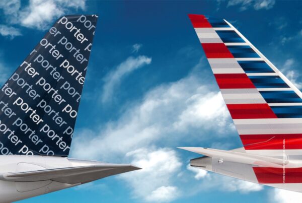 This image shows the tails of two airplanes against a blue, cloud-streaked sky. The tail on the left has Porter Airlines livery. The tail on the right was American Airlines livery. Photo courtesy of American Airlines.